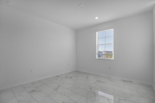 spare room with recessed lighting, marble finish floor, and baseboards