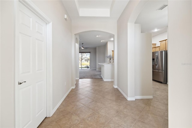 hallway with arched walkways, visible vents, and baseboards