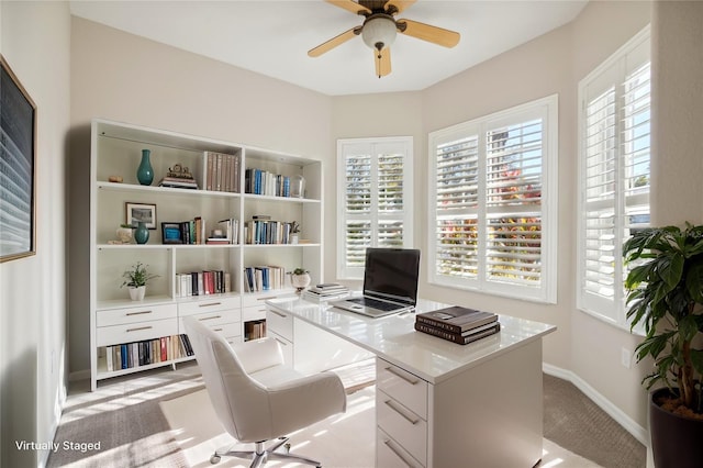 office area with light carpet, a ceiling fan, and baseboards