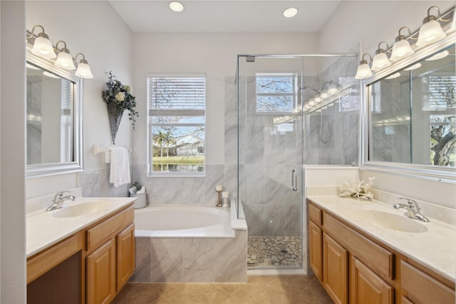 bathroom featuring a bath, a stall shower, two vanities, and a sink