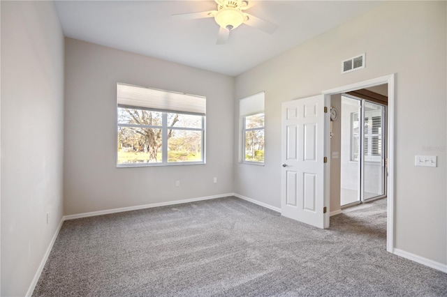 carpeted empty room featuring visible vents, baseboards, and a ceiling fan