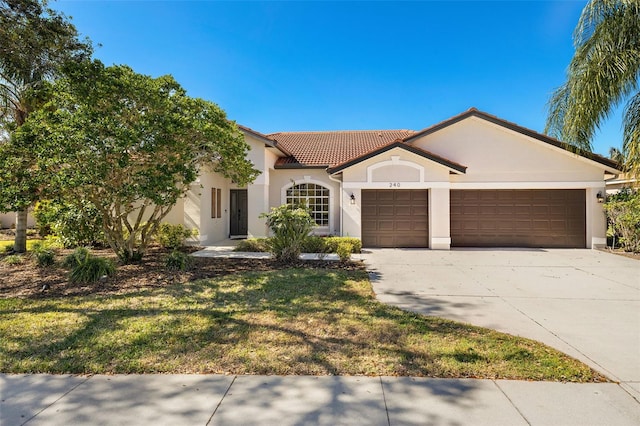 mediterranean / spanish home with an attached garage, a tiled roof, concrete driveway, stucco siding, and a front yard