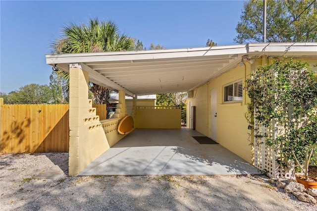 view of parking / parking lot with a carport and fence