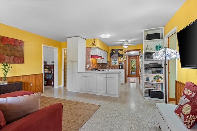 living room with light speckled floor, wainscoting, ceiling fan, and wood walls