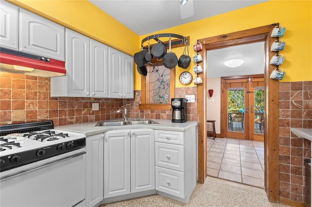 kitchen featuring white cabinets, light countertops, white gas stove, under cabinet range hood, and a sink