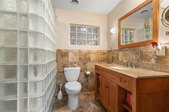 full bathroom with toilet, visible vents, tile walls, and vanity