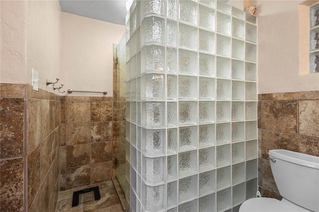 full bath featuring a walk in shower, toilet, wainscoting, and tile walls