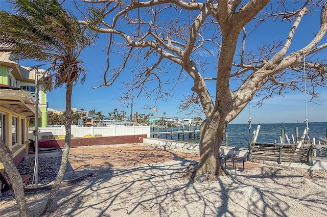 view of yard with a boat dock, a water view, and fence