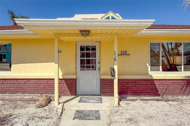 view of exterior entry with covered porch and brick siding