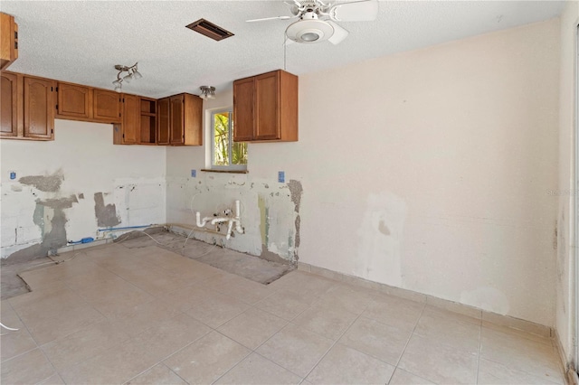 kitchen featuring visible vents, a ceiling fan, brown cabinets, a textured ceiling, and light tile patterned flooring