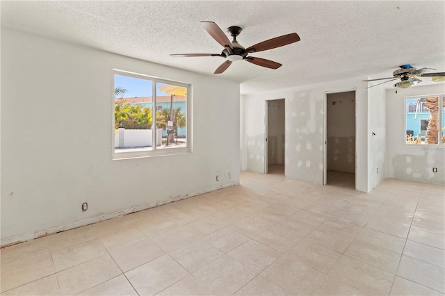 unfurnished bedroom featuring a ceiling fan, multiple windows, and a textured ceiling