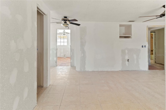 tiled spare room with a ceiling fan, visible vents, and a textured ceiling