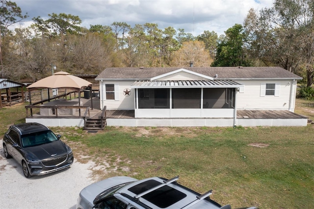 rear view of house with a lawn, a wooden deck, and a sunroom