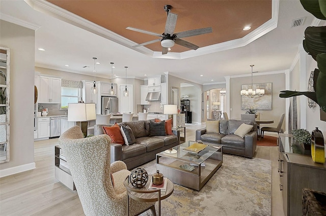 living room with a tray ceiling, arched walkways, light wood-style floors, and visible vents