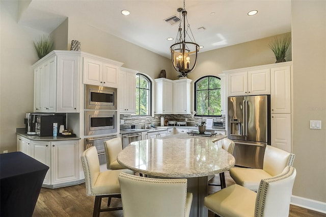 kitchen featuring stainless steel appliances, visible vents, white cabinets, and decorative backsplash