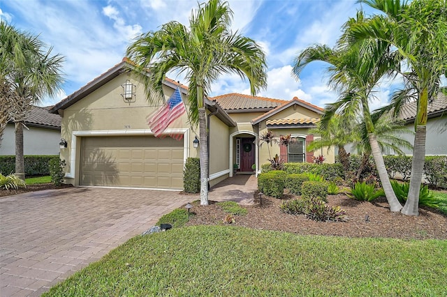 mediterranean / spanish house featuring a garage, decorative driveway, stucco siding, and a tile roof