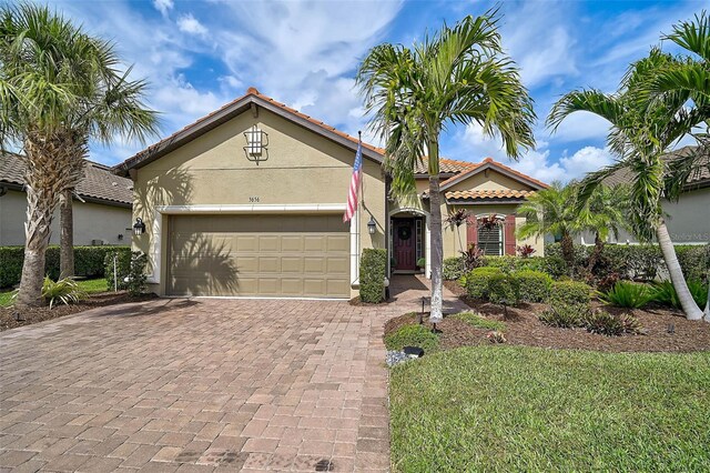 mediterranean / spanish home featuring decorative driveway, a tiled roof, an attached garage, and stucco siding