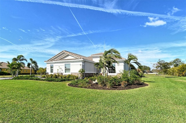 view of front of home featuring stone siding, a tile roof, a front yard, and stucco siding