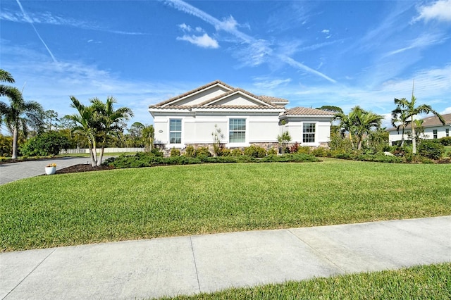 view of front of home featuring a front yard, stone siding, a tiled roof, and stucco siding