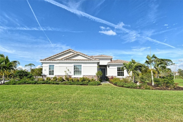 view of front of house featuring stone siding, a tiled roof, a front lawn, and stucco siding