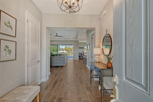 corridor featuring wood tiled floor, baseboards, and a chandelier