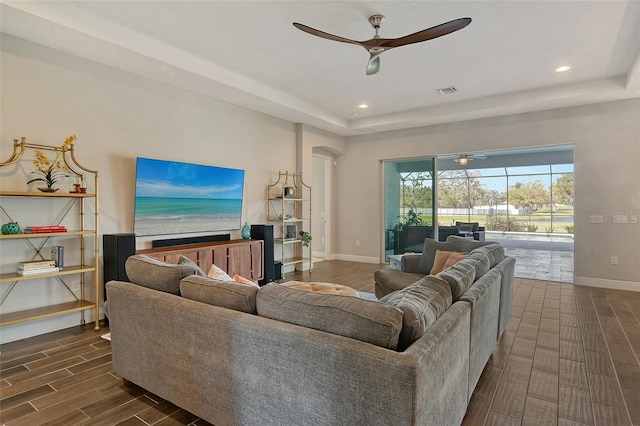 living room featuring a ceiling fan, wood tiled floor, baseboards, and a tray ceiling