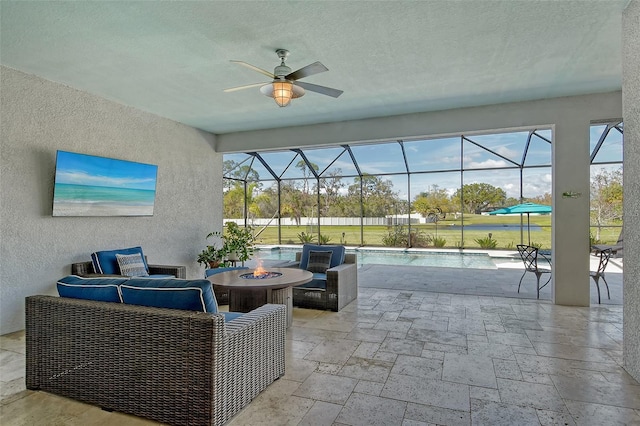 view of patio / terrace with a fire pit, a lanai, a ceiling fan, and an outdoor pool