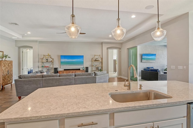 kitchen featuring light stone counters, recessed lighting, a sink, white cabinetry, and open floor plan