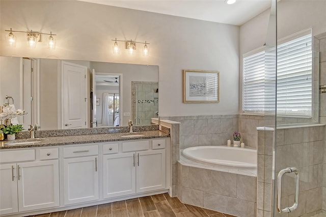 bathroom featuring a bath, a stall shower, double vanity, and a sink