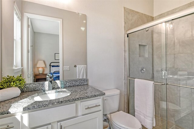 ensuite bathroom featuring vanity, a stall shower, ensuite bath, and toilet