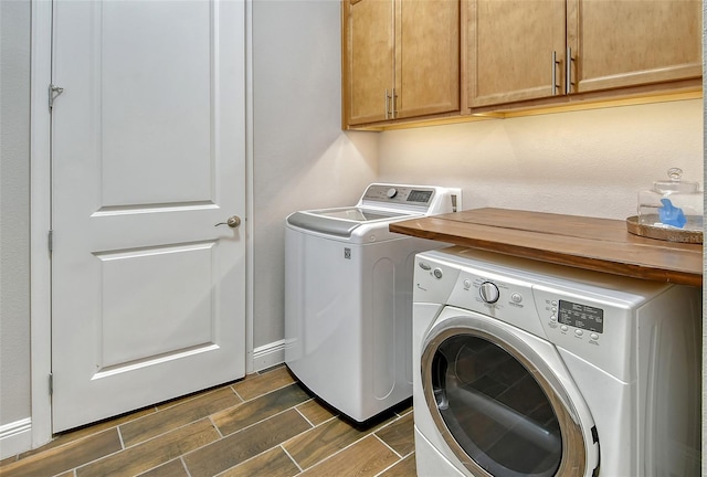 laundry area featuring washing machine and dryer, cabinet space, baseboards, and wood tiled floor