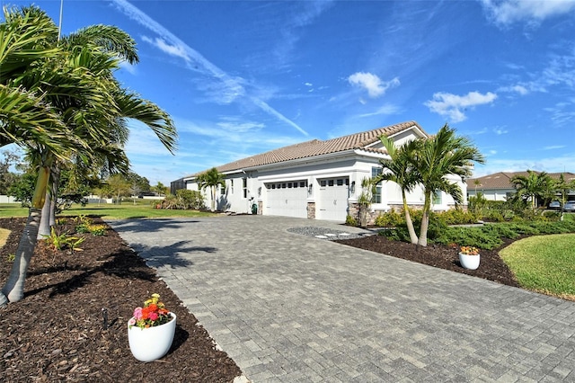 view of front of property featuring decorative driveway, an attached garage, a tile roof, and stucco siding