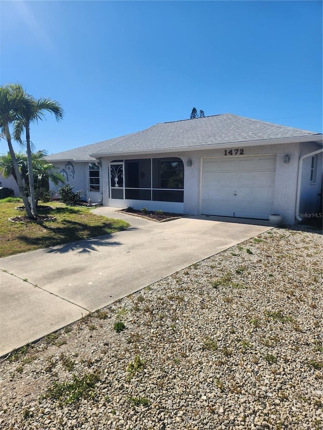 single story home featuring a garage, a sunroom, driveway, and stucco siding