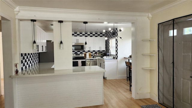 kitchen featuring decorative backsplash, appliances with stainless steel finishes, ornamental molding, a peninsula, and white cabinetry