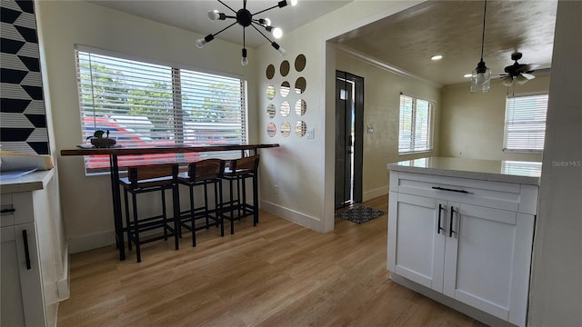 kitchen featuring light wood-type flooring, white cabinets, crown molding, and light countertops