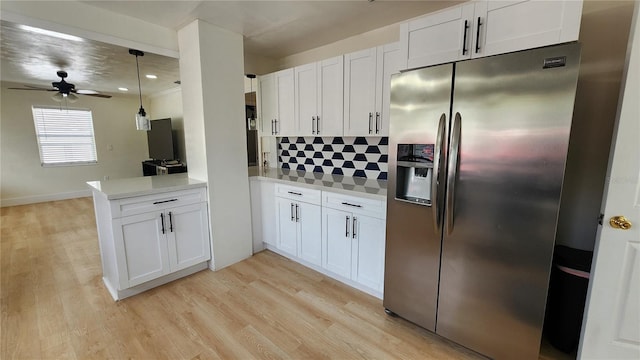 kitchen with light countertops, backsplash, light wood-style flooring, white cabinets, and stainless steel fridge with ice dispenser