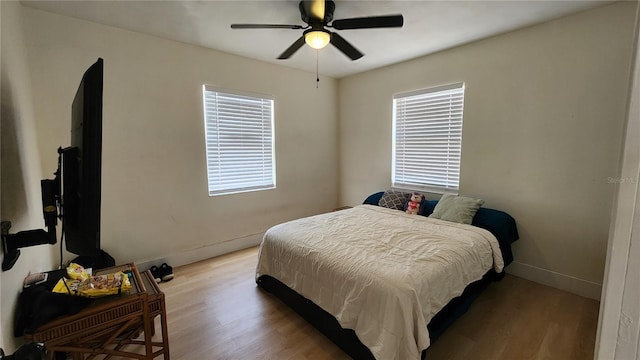 bedroom with a ceiling fan, baseboards, and light wood finished floors