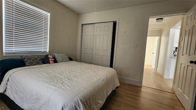 bedroom with a closet, wood finished floors, and baseboards