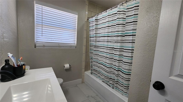 bathroom with shower / tub combo, baseboards, toilet, marble finish floor, and a sink