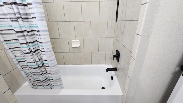 bathroom with shower / tub combo with curtain and a textured wall