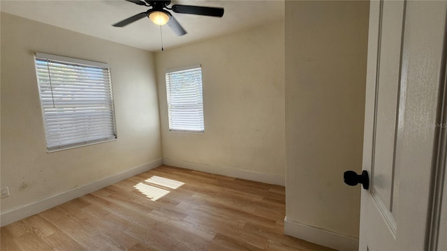 unfurnished room with ceiling fan, light wood finished floors, and baseboards