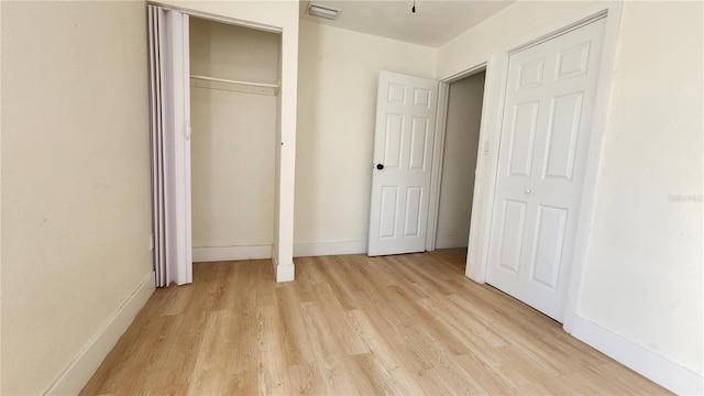 unfurnished bedroom with light wood-style flooring, a closet, visible vents, and baseboards