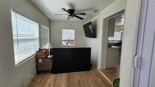 interior space featuring ceiling fan, wood finished floors, visible vents, and baseboards