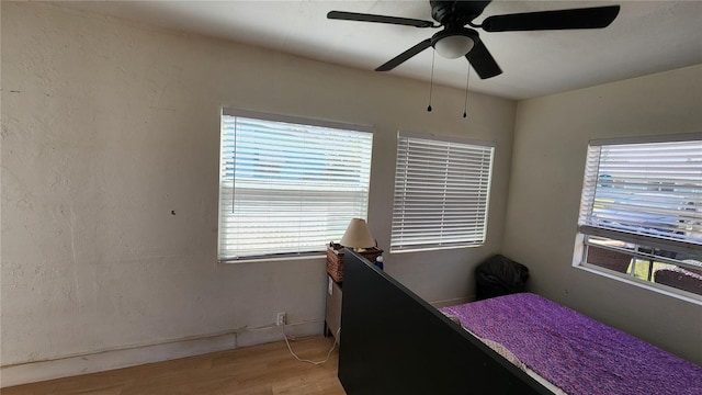 bedroom with light wood-style floors, multiple windows, and a ceiling fan