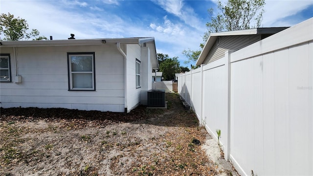 view of side of home featuring fence and central AC