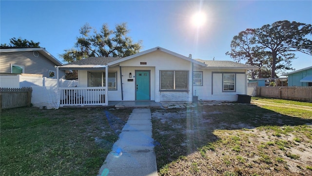 bungalow-style home featuring a front yard, covered porch, and fence