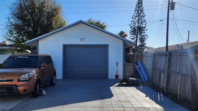 detached garage featuring driveway and fence