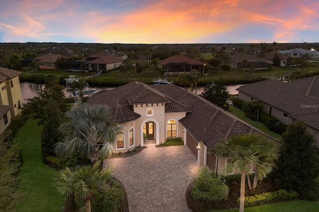 view of front of home featuring a tiled roof, a residential view, decorative driveway, and stucco siding