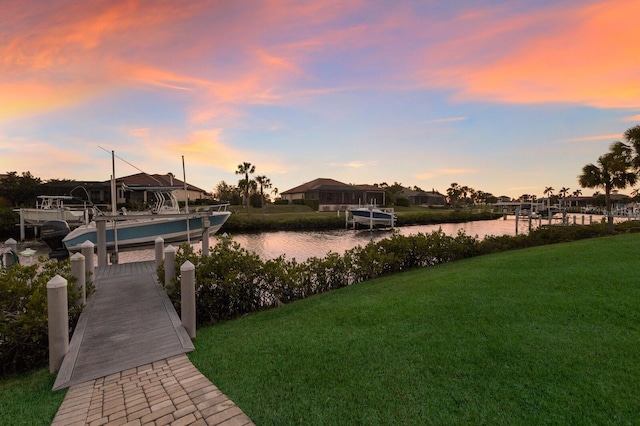 view of dock with a water view, a lawn, and boat lift