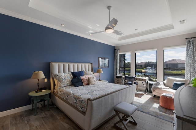 bedroom with visible vents, a tray ceiling, baseboards, and ornamental molding